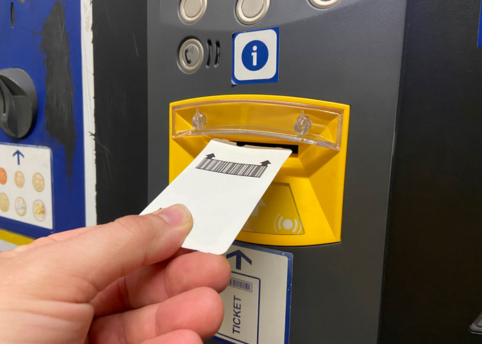 Parking ticket with barcode going into machine